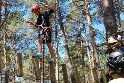 Unos aventureros se enfrentan a los retos del parque de cuerdas del Amogable ante la atenta mirada de una monitora. HDS