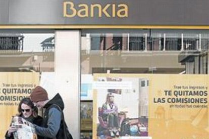 Unos turistas en Sevilla, ante una sede de Bankia.-REUTERS / MARCELO DEL POZO