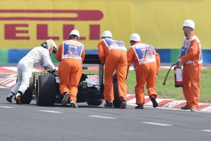 Alonso empuja su coche hasta el 'pit lane'.-Foto: ANDREJ ISAKOVIC / AFP