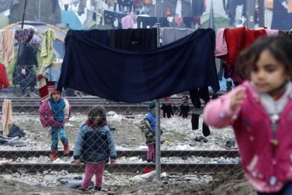 Niños refugiados juegan entre ropas colgadas para secar entre alambradas en un campo de refugiados de Idomeni (Grecia), junto a la frontera con Macedonia, este miércoles.-AP / BORIS GRDANOSKI