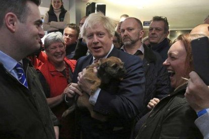 El primer ministro británico, Boris Johnson, sostiene un perro durante un encuentro con Paul Howell, el recién elegido diputado del Partido Conservador en Sedgefield, en el noreste de Inglaterra.-LINDSEY PARNABY (AP)