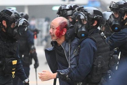 La policía se lleva a un manifestante herido en Hong Kong.-AFP / PHILIP FONG