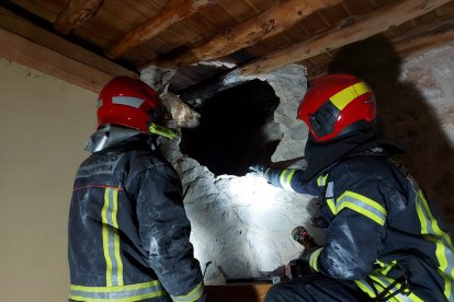 Los bomberos miran por un hueco abierto para extinguir el incendio en Castillejo de Robledo. HDS