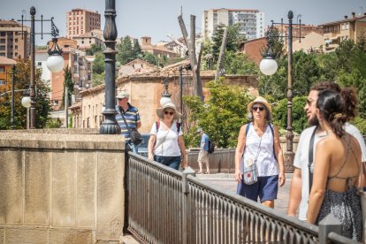 Turistas cruzando el puente de piedra.