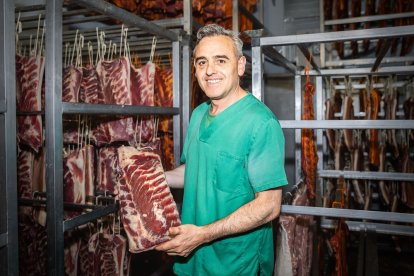 Santiago Alonso posa con una de las pancetas que preparan para hacer torreznos.