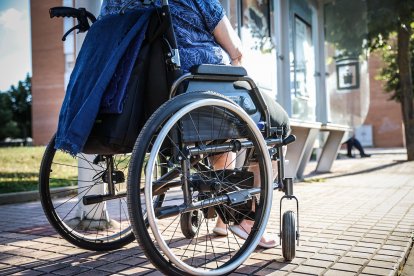 Una mujer en silla de ruedas frente a una parada de autobús.