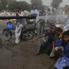 Voluntarios pulverizan a la gente en Karachi.-FAREED KHAN