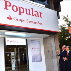 Directivos del Santander ante una de las primeras oficinas del Popular que ya ha adoptado la imagen corporativa del grupo cántabro, en Madrid-EL PERIÓDICO