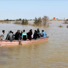 Iranís de la provincia de Golestan, anegada por las lluvias, en una barcaza a finales de marzo.-REUTERS