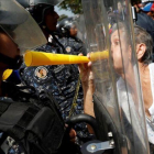 Una manifestantes de la oposición se encara con los antidisturbios en la protesta de este sábado en Caracas.-REUTERS / CARLOS GARCÍA RAWLINS