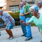 Un grupo de pensionistas juega a petanca en un parque.-ALBERT BERTRAN