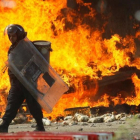 Un policía pasa frente a un camión en llamas durante las protestas contra la reforma educativa en Oaxaca.-REUTERS / JORGE LUÍS PLATA