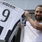 El delantero Gonzalo Higuaín muestra a sus aficionados su nueva camiseta de la Juventus.-MARCO BERTORELLO / AFP