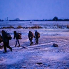 Migrantes y refugiados caminan por un campo cubierto de nieve tras cruzar la frontera de Macedonia con Serbia, cerca de la población de Miratovac, este domingo.-AFP / DIMITAR DILKOFF
