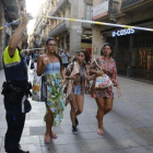 Unos turistas pasan bajo un cordón policial en la calle de Portaferrissa.-ÁLVARO MONGE