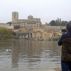 Una persona realiza una fotografía de las Aceñas de Olivares y la catedral desde la playa de los Pelambres.-M.D.