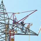 Un grupo de trabajadores preparan la sustitución del tendido de electricidad de una torre de alta tensión.-ARCHIVO