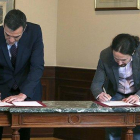 Pedro Sánchez y Pablo Iglesias firman el preacuerdo de coalición, el martes pasado en el Congreso.-DAVID CASTRO