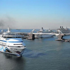 Un ferri humeante entra por la Bocana Nord junto al muelle Adossat repleto de grandes cruceros.-JOAN CORTADELLAS