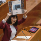 Sandra Miguez muestra, en el pleno de las Corts, un tuit del grupo popular en el que se hace eco del titular de una entrevista a un profesor, criticado por la diputada de Podemos durante su intervención.-MIGUEL LORENZO