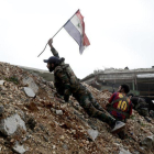 Un soldado del régimen sirio coloca una bandera en una zona de combate.-HASSÁN AMMAR / AP