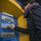 Una clienta bancaria utiliza su tarjeta en un cajero automático-JOAN CORTADELLAS