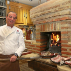 Alberto Sánchez, propietario del restaurante La Encina, se dispone a asar unos cuartos de lechazo.-BRÁGIMO