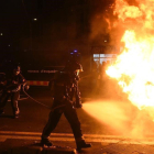 Bomberos apagan un contenedor en llamas en las protestas de los manifestantes contra un acto de Vox.-JORDI COTRINA