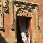 Pilar Fernández de Trocóniz, en la denominada Ventana del Obispo, que corona el patio del Castillo del Buen Amor, con su tinto CBA. En la foto pequeña, los viñedos que rodean el Castillo del Buen Amor, con la torre del homenaje al fondo.-ARGI