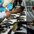Un miembro de una banda entrega su arma en una ceremonia en Cali, el pasado julio-AFP / LUIS ROBAYO