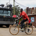 Un ciclista pasa por delante de un vehículo antidisturbios en las chabolas de Kibera, en Nairobi, el 7 de agosto.-REUTERS