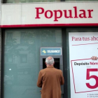 Un hombre saca dinero de un cajero del Popular en Madrid.-REUTERS / ANDREA COMAS