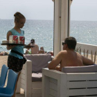 Una camarera en un chiringuito de playa trabajando durante el verano.-MAITE CRUZ (EL PERIÓDICO)