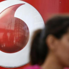 Una mujer habla por móvil frente a un anuncio de Vodafone.-REUTERS