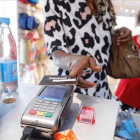 Una consumidora paga con trjeta en una tienda de ropa.-