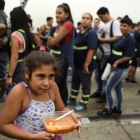 Una niña lleva su ración de comida servida durante una protesta social en Buenos Aires contra la pobreza, el 15 de marzo.-AFP / EITAN ABRAMOVICH