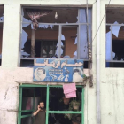 Un hombre habla por su teléfono móvil desde la entrada a su tienda dañada por un atentado cerca del Ministerio de Defensa en Kabul, Afganistán.-JAWAD JALALI