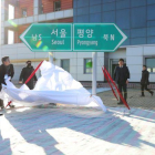 Oficiales norcoreanos y surcoreanos destapan dos señales que indican la dirección de las capitales de ambos países en la estación de tren de Panmun en Kaesong.-EPA / KOREA POOL