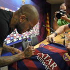 Dani Alves firma una camiseta antes de su comparecencia.-Foto:  AFP / LLUÍS GENÉ