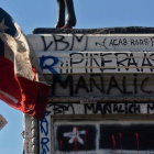 Un manifestante con una bandera de Chile pasa junto a la base de una estatua ecuestre repleta de pintadas.-CLAUDIO REYES (AFP)