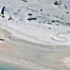 SOS escrito en la arena de playa por  Linus y Sabina Jack.-US NAVY