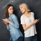 Una chica espía el móvil de su amiga.-123RF