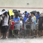 Un grupo de personas hace cola bajo una intensa lluvia en una tienda de ultramarinos en Carolina del Norte.-AP/ CHUCK LIDDY