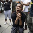 Un hombre reza mientras la policía dispersa a los manifestantes en Ferguson tras el asesinato de Michael Brown.-Foto:  AP / Jeff Roberson
