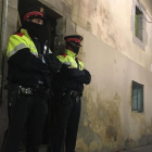 Dos mossos ante el portal de la calle de la Riera Alta donde se ha cometido el crimen.-/ GUILLEM SÀNCHEZ