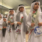 Niños qatarís con flores e imágenes del emir Al Thani reciben a ciudadanos de Kuwait y Omán, países que no se han sumado al boicot, en el aeropuerto de Doha.-REUTERS / NASEEM ZEITOON