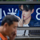 Un hombre habla con su móvil ante un anuncio de Xiaomi.-WANG ZHAO (AFP)