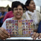 Una mujer muestra la foto de los estudiantes de Ayotzinapa.-AFP / YURI CORTEZ