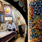 Dos hombres iranís conversan dentro de su negocio de alfombras en el Gran Bazar de Teherán. /-EFE / ABEDIN TAHERKENAREH