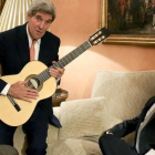 Kerry con la guitarra española que le ha regalado Margallo, sentado en el sofá, esta tarde en el Palacio de Viana, en Madrid.-EFE / BALLESTEROS